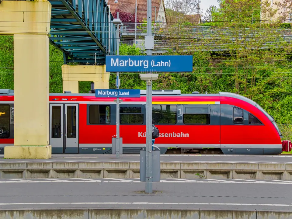 Roter Zug auf dem Bahnsteig des Bahnhofs Marburg, der den öffentlichen Verkehr in Deutschland präsentiert.