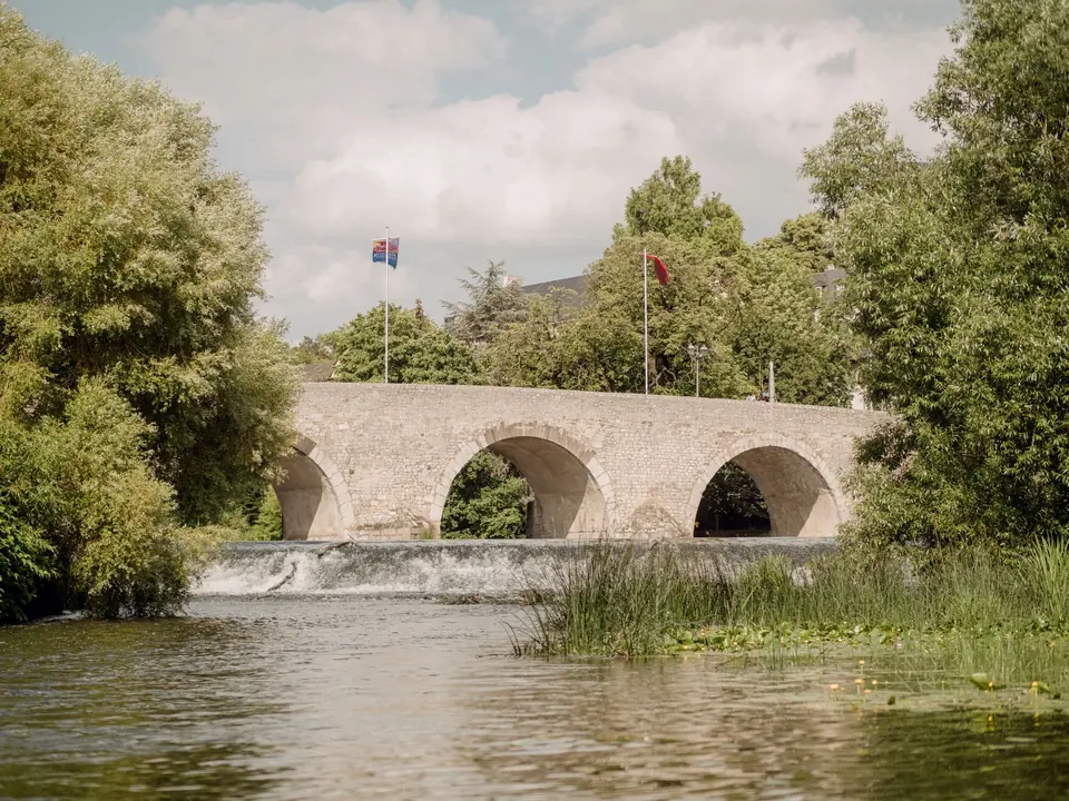 Eine historische Steinbrücke in Wetzlar, Deutschland, die einen ruhigen Fluss umspannt, umgeben von üppigem Grün.